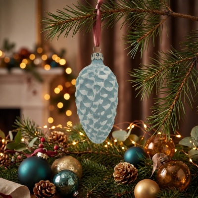 Tannenzapfen-Christbaumanhänger aus eisblauem Glas mit weißem Frostdekor an einer Tannenbranche.