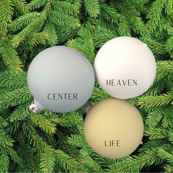 3 verschiedene Christbaumkugeln aus Glas in Softblau, weiß und grün mit 6cm Durchmesser auf grünen Tannen dekorativ zum Vergleich dargestellt