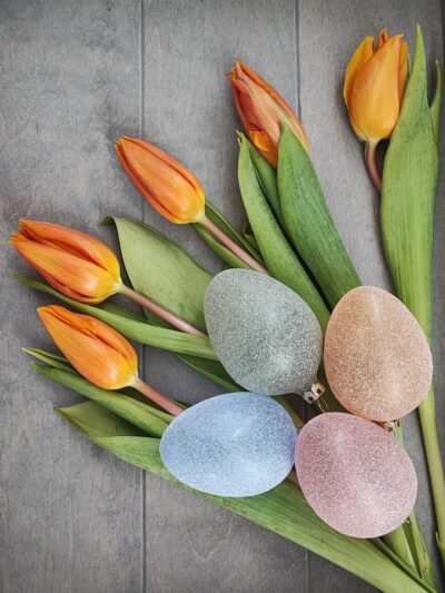 4 Ostereier aus Glas in einem transparenten Glitzer Design in blau, orange, grün und rot mit Tulpen dekoriert